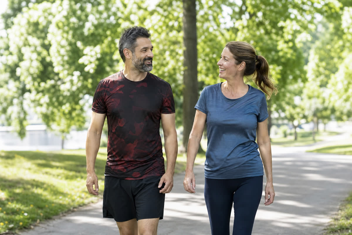 Middle-aged couple brisk walking outdoors in a park for heart health and cholesterol control