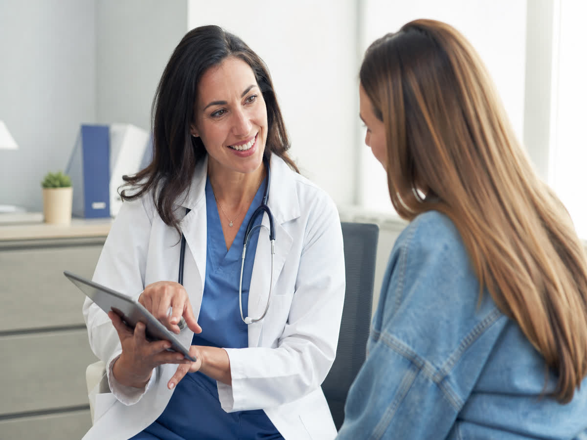 Friendly female doctor in a white coat consulting a patient about headaches in a bright clinic