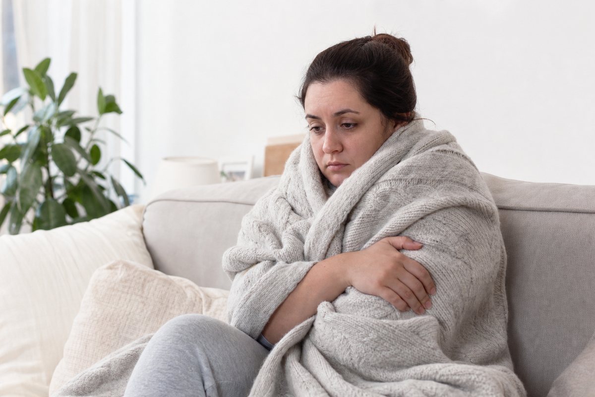 Woman wrapped in a blanket feeling cold and fatigued representing hypothyroidism symptoms