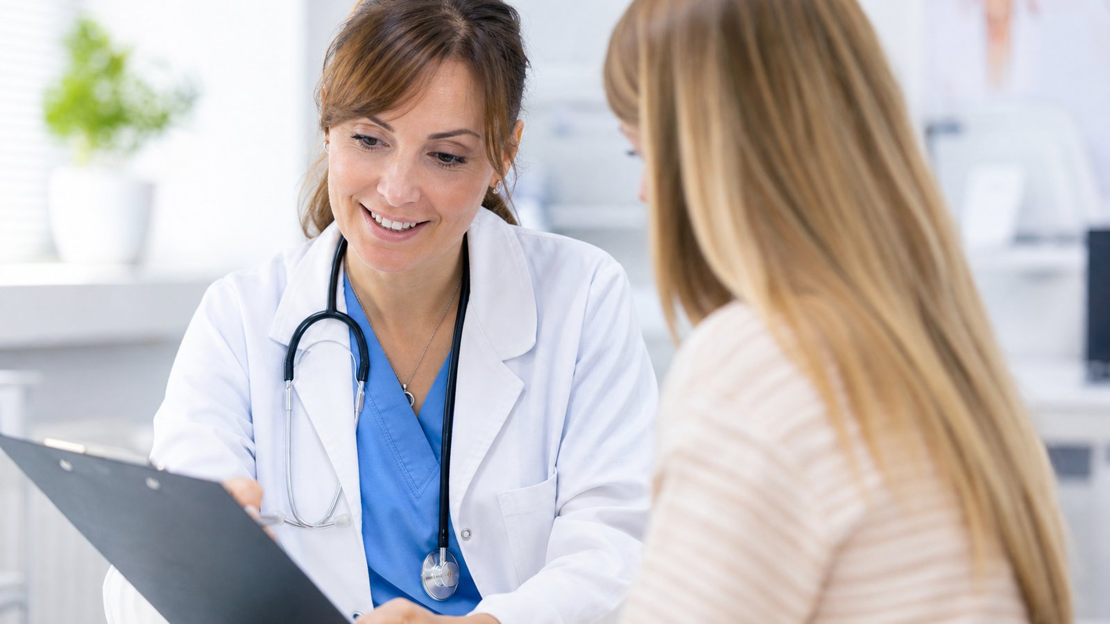 Friendly female doctor in a white coat reviewing blood test results with a patient in a bright clinic